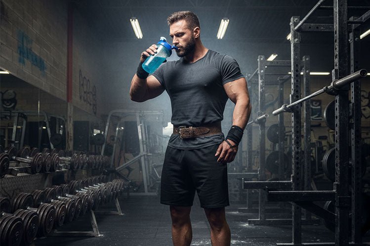 Guy in gym drinking a stim-free pre-workout from a shaker bottle.
