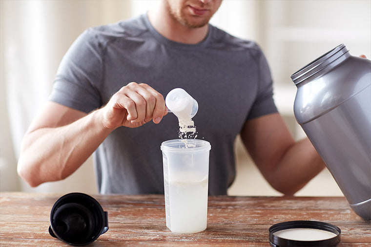 Man scooping supplements into a shaker bottle.