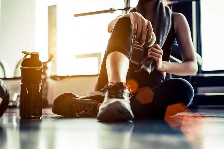 Woman sitting on the floor after a workout with shaker bottle