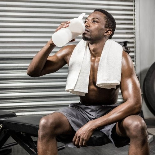 Man drinking his protein shake at the gym in between sets