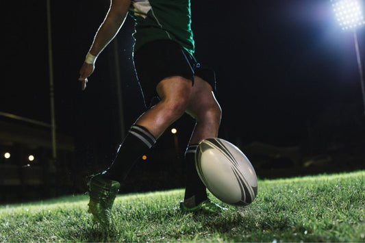 Man kicking rugby ball on the field.