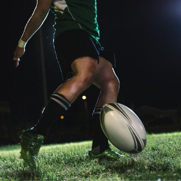 Man kicking rugby ball on the field.