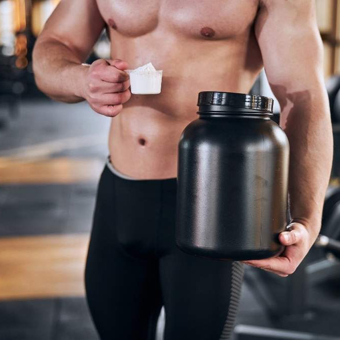 Shirtless man holding a container of creatine